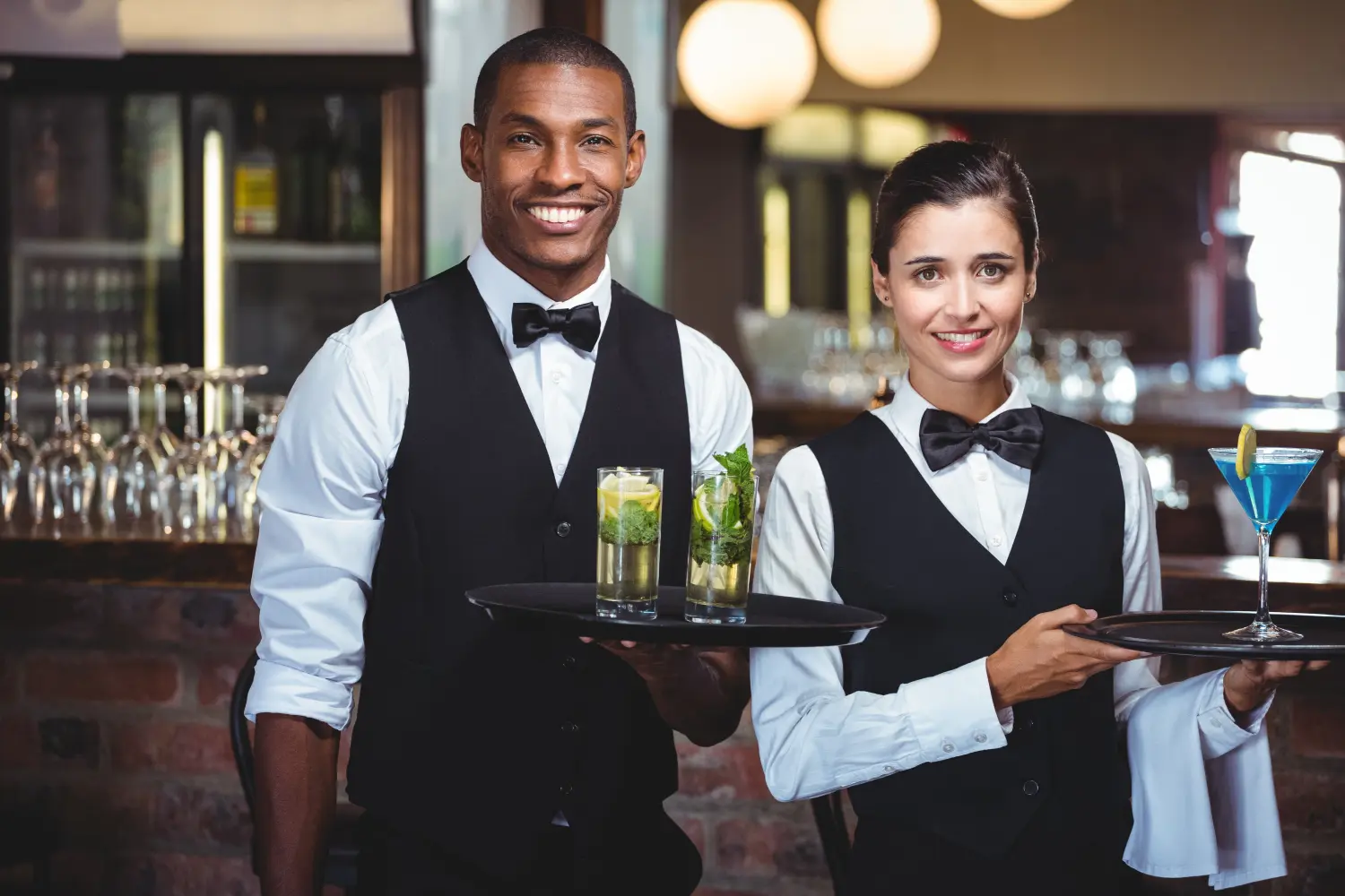 Kellner und Kellnerin gemischter Abstammung halten ein Serviertablett in der Hand